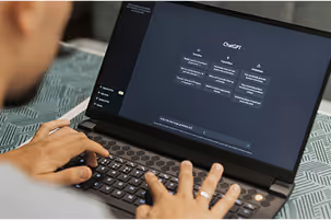 Person typing on a laptop with a dark interface displaying CloudGPT options on screen.