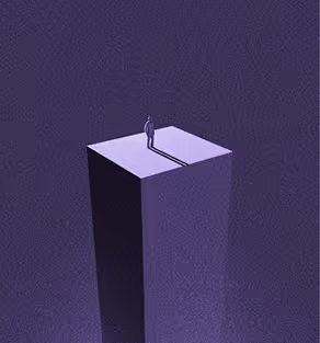 Silhouette of a person standing alone on a tall, narrow platform casting a long shadow.