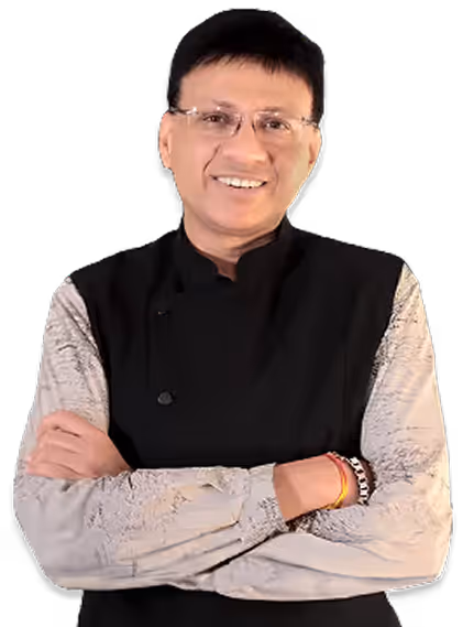 Smiling man wearing glasses with arms crossed, dressed in a black vest over a patterned light-colored shirt.
