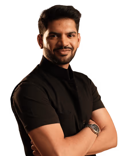 A confident man with folded arms wearing a black shirt and a wristwatch, smiling against a black background.