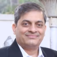Portrait of a middle-aged man with short gray hair, wearing a suit jacket and white shirt, smiling softly.