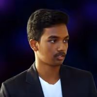 Young man with short black hair wearing a black blazer and white shirt looking to his side against a dark blue background.