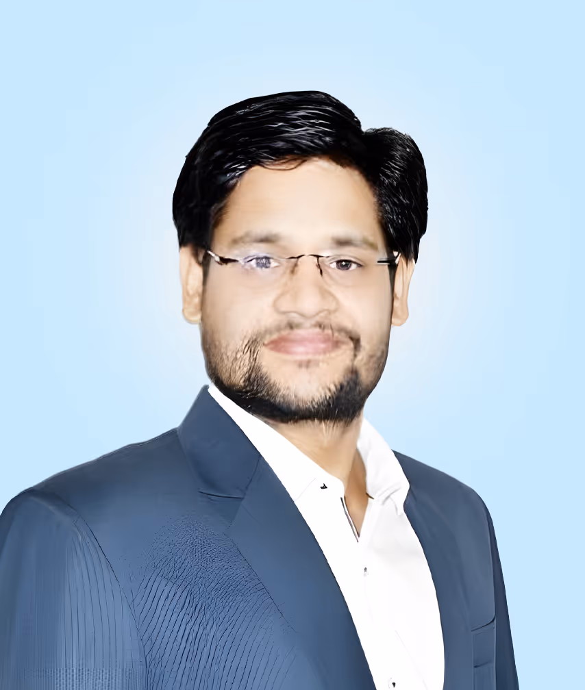 Portrait of a man with glasses, beard, and dark hair, wearing a blue suit and white shirt against a light blue background.